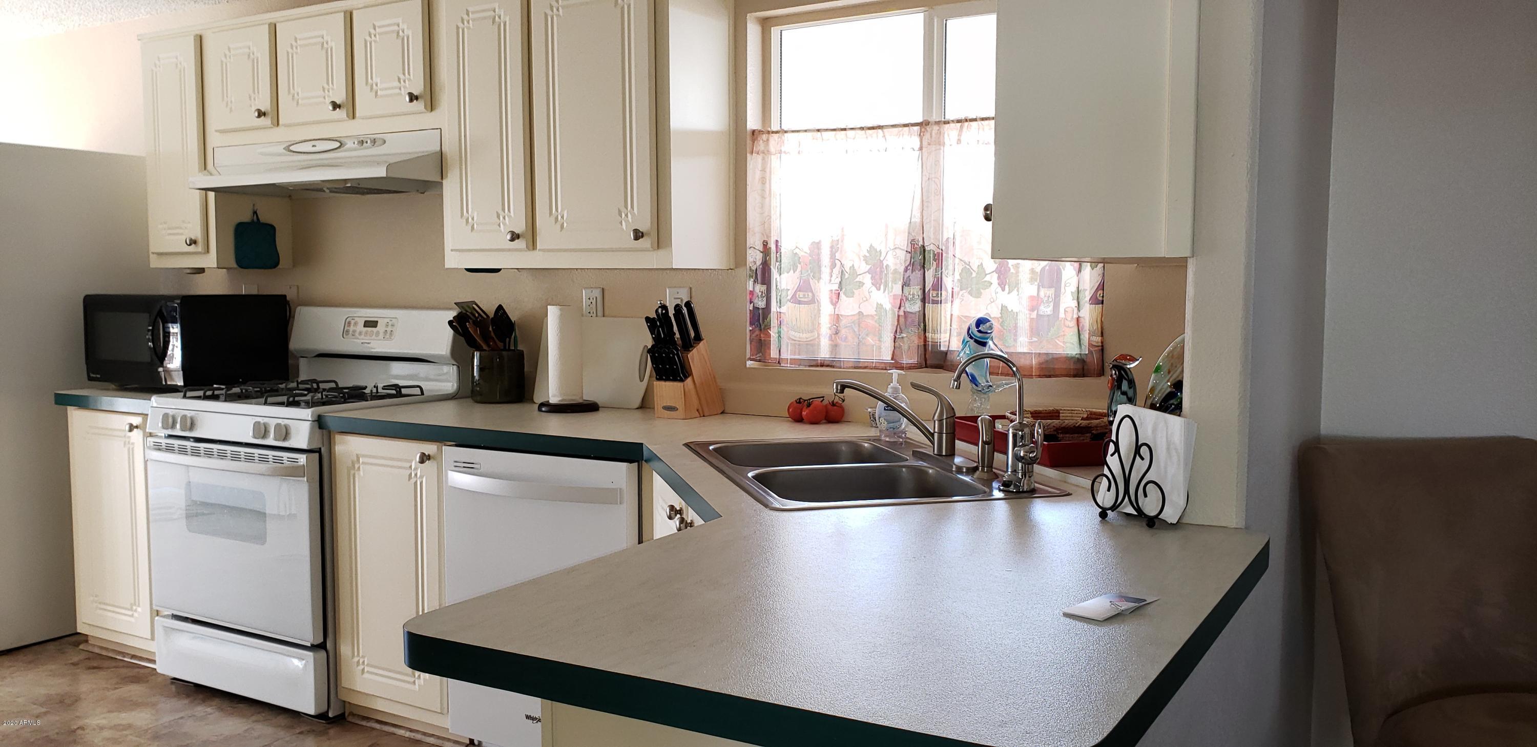 301 South Signal Butte Road, Unit 705 Apache Junction, AZ 85120 - Photo 13 of 50 a kitchen with stainless steel appliances a sink a stove and a microwave