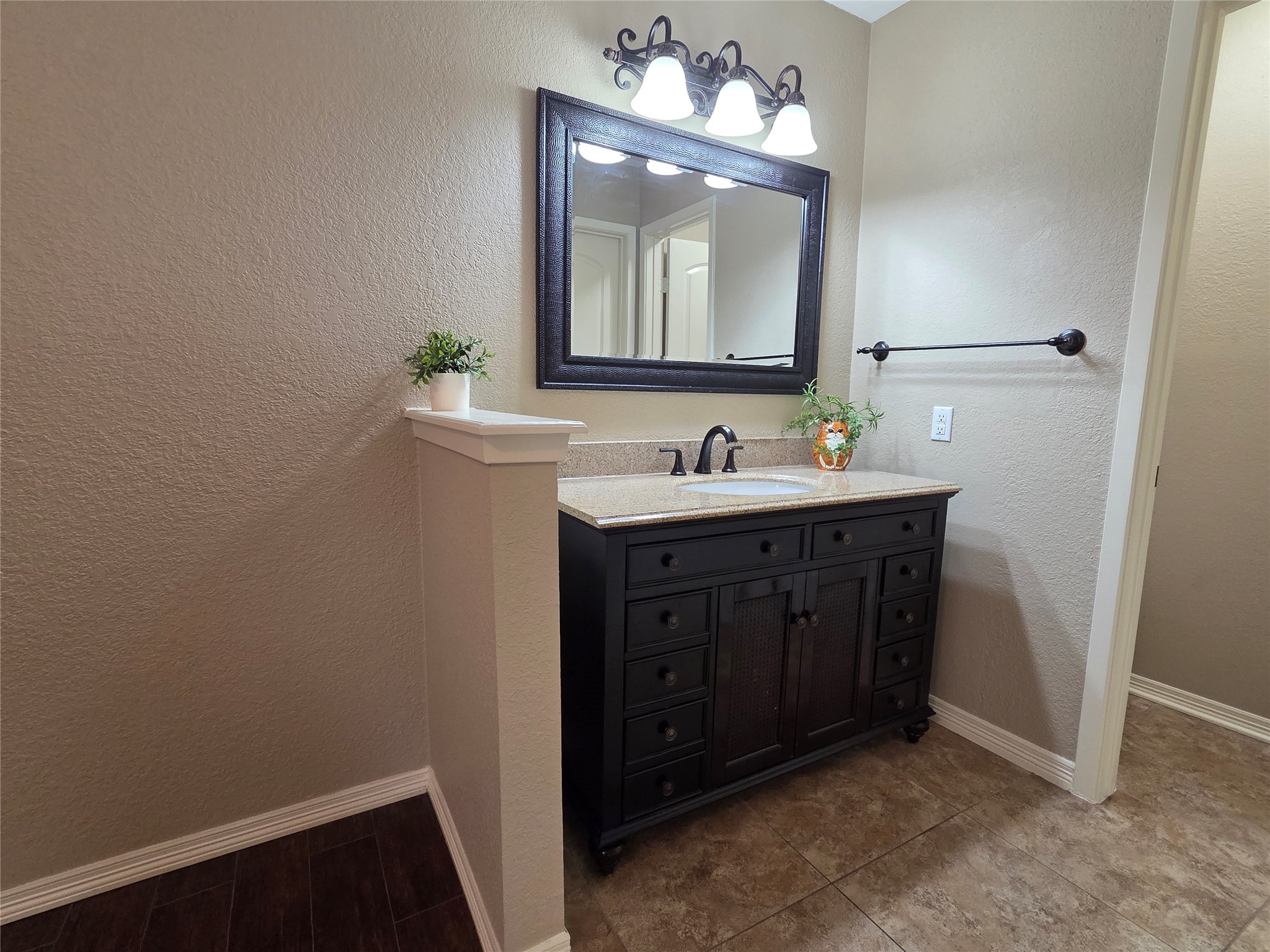 4203 Spinks Creek Lane Spring, TX 77388 - Photo 11 of 14 This photo showcases a stylish bathroom with a dark wood vanity, granite countertop, and a large mirror. The space is well-lit with a three-light fixture and features neutral tile flooring and walls, adding a modern touch.