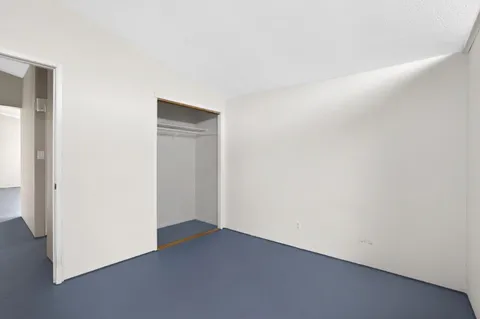 an empty room with wooden floor fireplace and a window