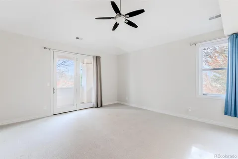an empty room with wooden floor chandelier fan and windows