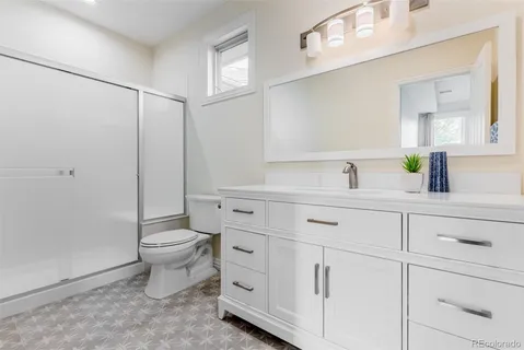 a bathroom with a granite countertop toilet sink and mirror