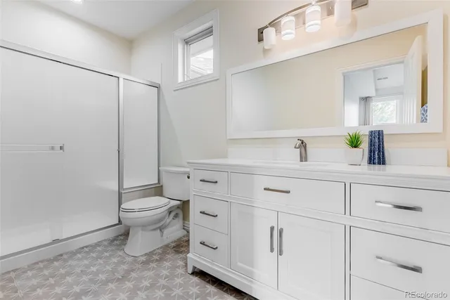 a bathroom with a granite countertop toilet sink and mirror