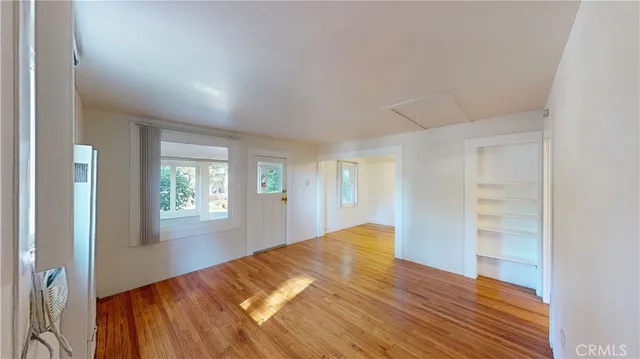 a view of empty room with wooden floor and fan