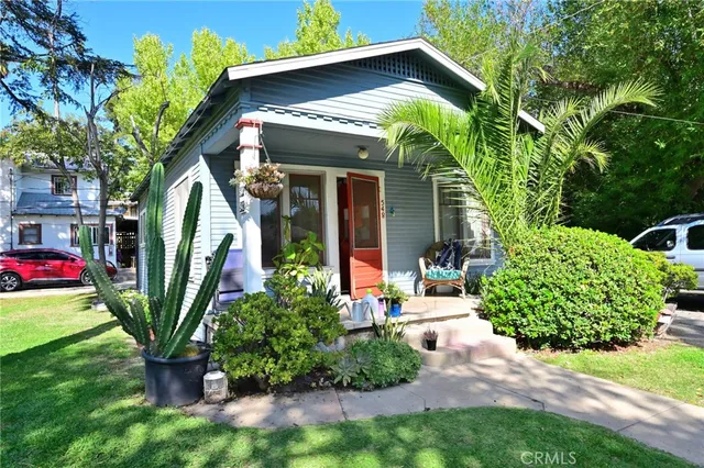 a view of a house with a small yard plants and a large tree