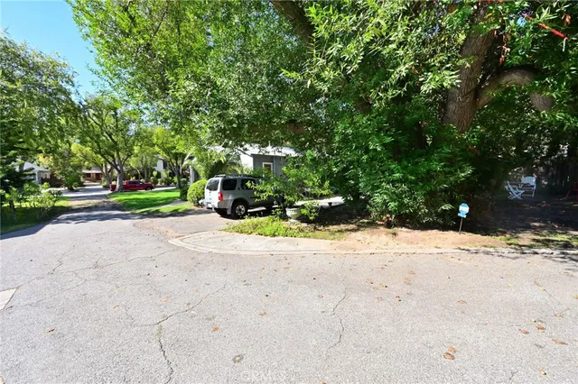 a view of street with a big yard and large trees