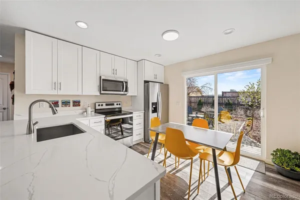a kitchen with stainless steel appliances granite countertop a stove top oven a sink dishwasher a dining table and chairs with wooden floor