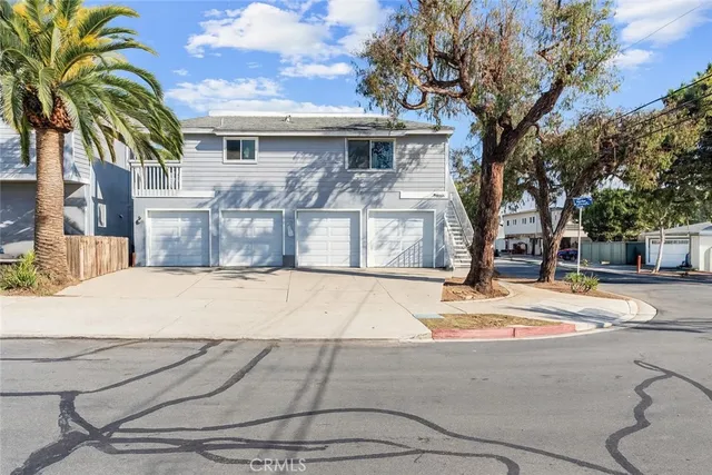 a view of a white house with a large tree