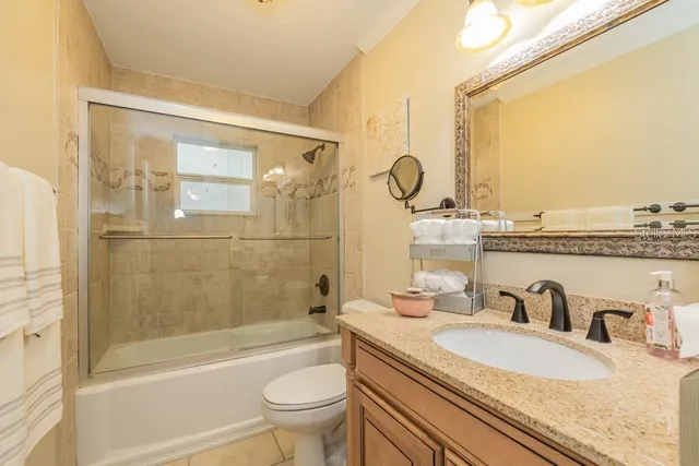 a bathroom with a granite countertop sink a toilet and shower