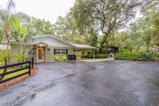 a view of a house with a yard and large trees