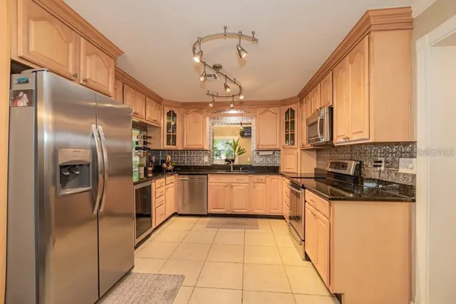 a kitchen with stainless steel appliances granite countertop a refrigerator a sink dishwasher a stove with white cabinets