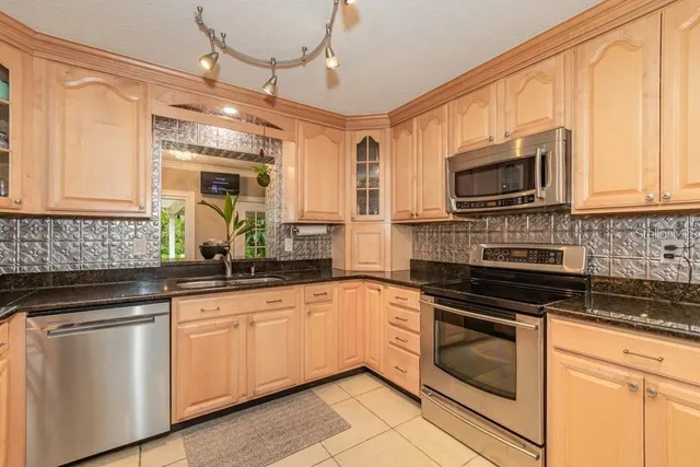 a kitchen with granite countertop cabinets stainless steel appliances and a window