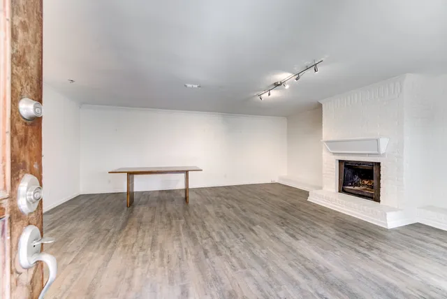 an empty room with wooden floor fireplace and windows