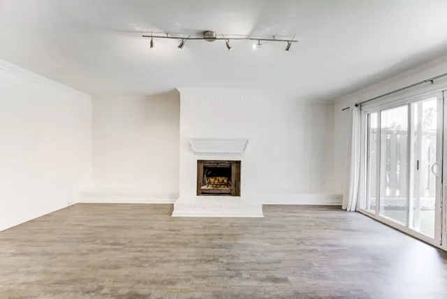 a view of empty room with wooden floor and fireplace