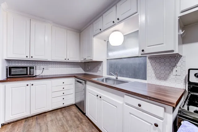 a kitchen with granite countertop white cabinets white appliances and wooden floor