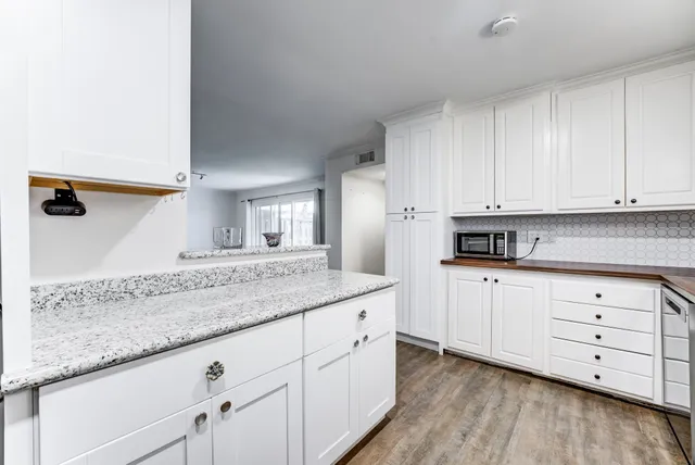 a kitchen with granite countertop white cabinets and white appliances