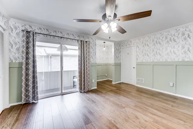 a view of empty room with wooden floor and fan