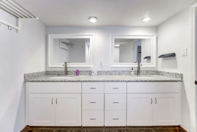 a bathroom with a granite countertop double vanity sink and mirror