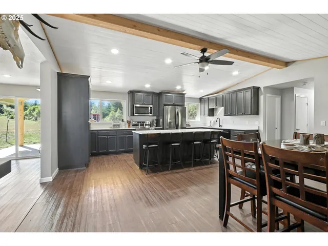 a kitchen with stainless steel appliances kitchen island granite countertop a table chairs and a refrigerator