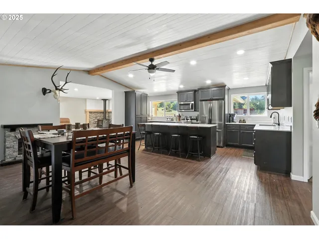 a kitchen with stainless steel appliances kitchen island granite countertop a table chairs and a refrigerator