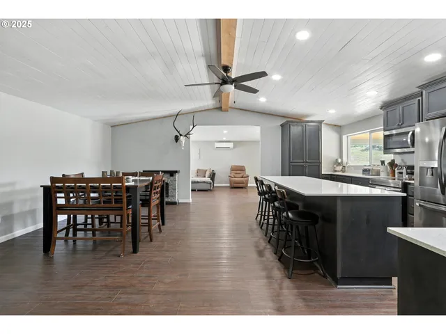 a kitchen with stainless steel appliances kitchen island granite countertop a table chairs and a refrigerator