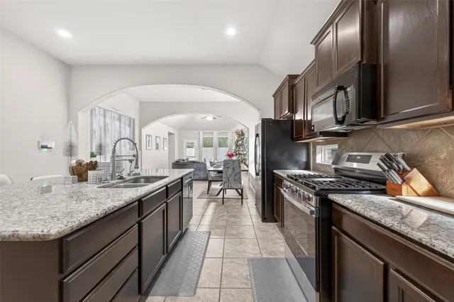 a kitchen with stainless steel appliances granite countertop a sink a stove and a wooden floors