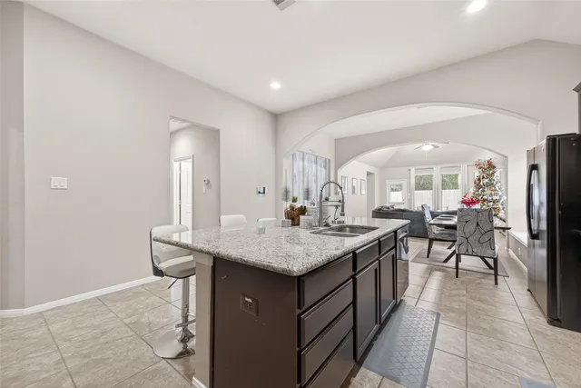 a dining hall with stainless steel appliances granite countertop a sink and a refrigerator