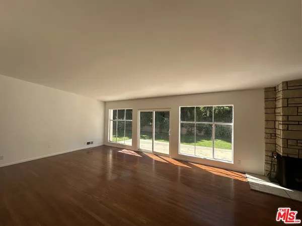 a view of an empty room with wooden floor and a fireplace