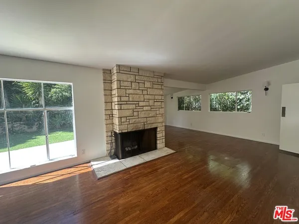 an empty room with windows fireplace and wooden floor