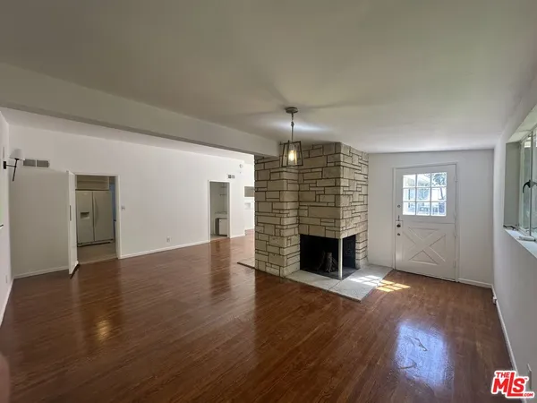 an empty room with wooden floor fireplace and windows