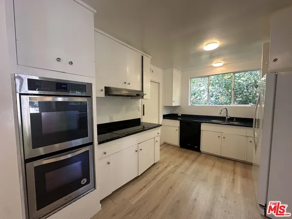 a kitchen with granite countertop white cabinets stainless steel appliances and a sink