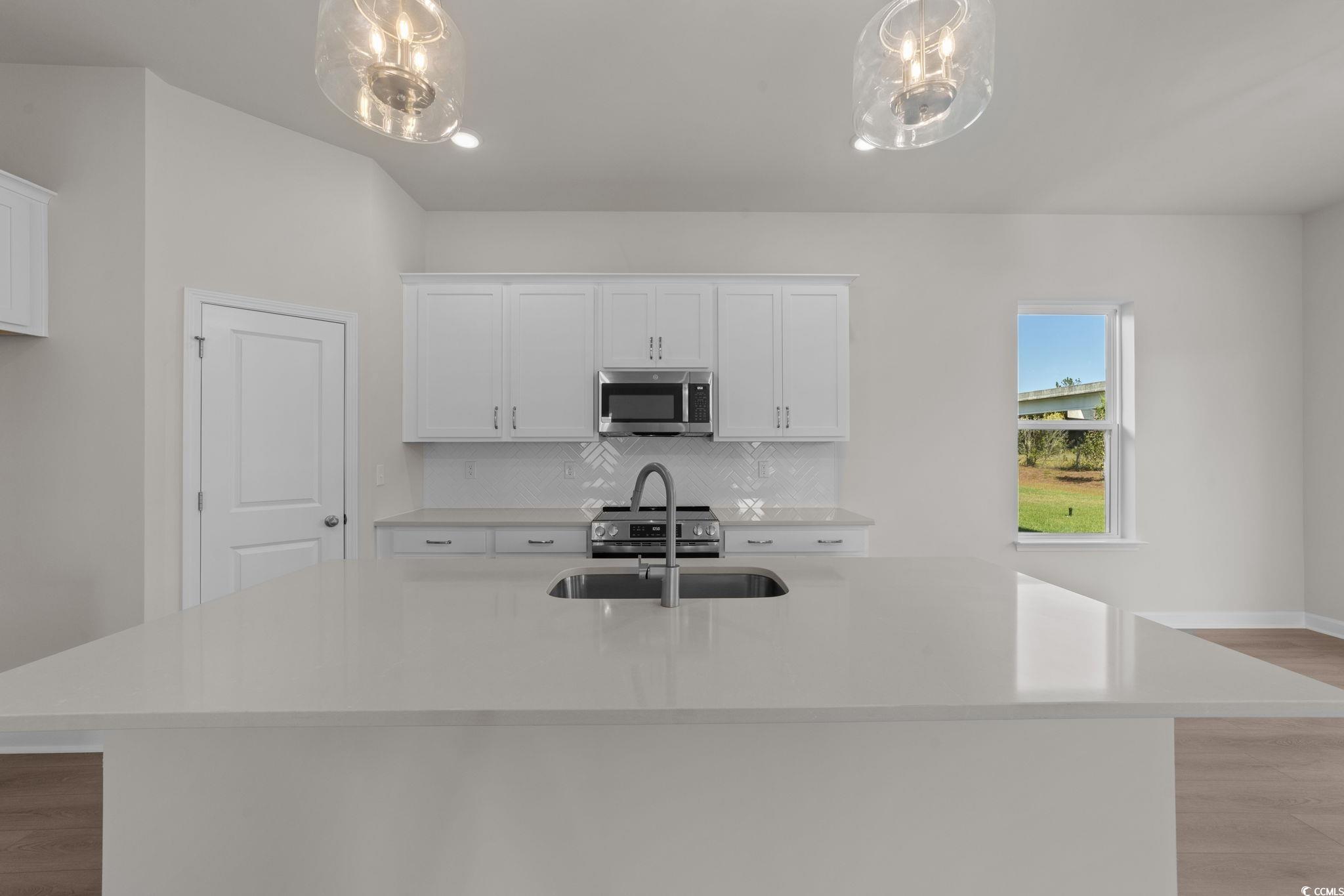 775 Ebb Tide Road Little River, SC 29566 - Photo 15 of 39 Kitchen with light wood finished floors, light stone countertops, white cabinets, and an island with sink