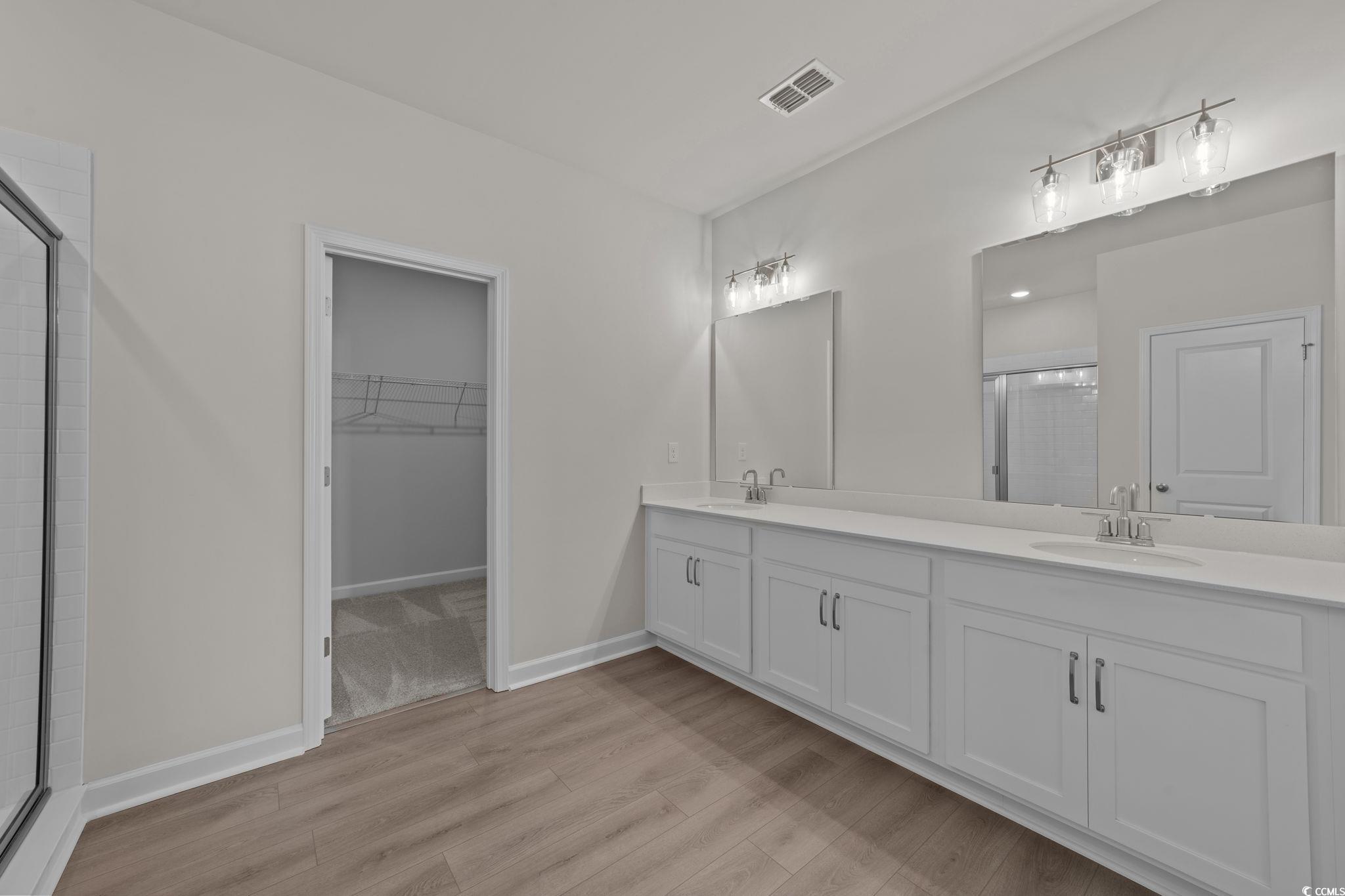 775 Ebb Tide Road Little River, SC 29566 - Photo 18 of 39 Bathroom featuring a shower stall, double vanity, light wood-type flooring, and a spacious closet