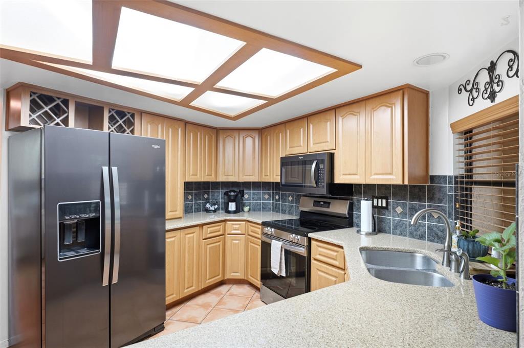 5227 Suwannee Road Weeki Wachee, FL 34607 - Photo 18 of 62 a kitchen with stainless steel appliances granite countertop a refrigerator a sink a stove a microwave a counter space and cabinets