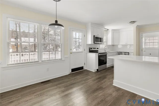 a kitchen with granite countertop a stove a sink dishwasher a refrigerator and white cabinets with wooden floor