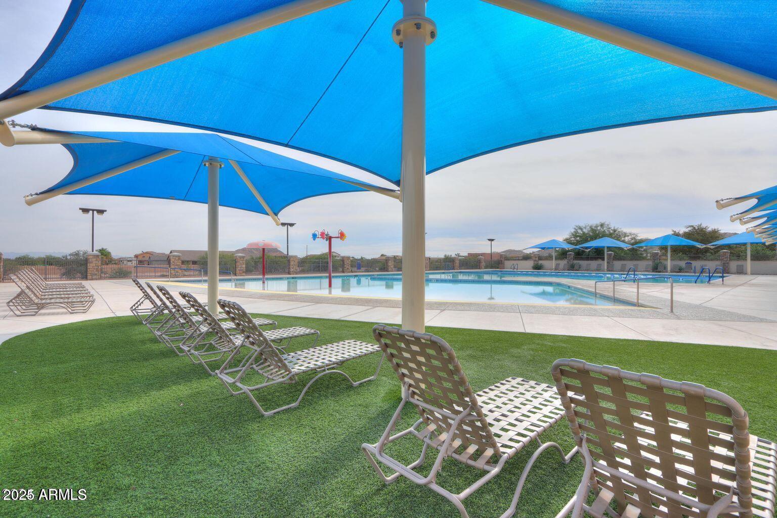 2496 West Tanner Ranch Road San Tan Valley, AZ 85144 - Photo 22 of 25 a view of a swimming pool with lawn chairs under an umbrella