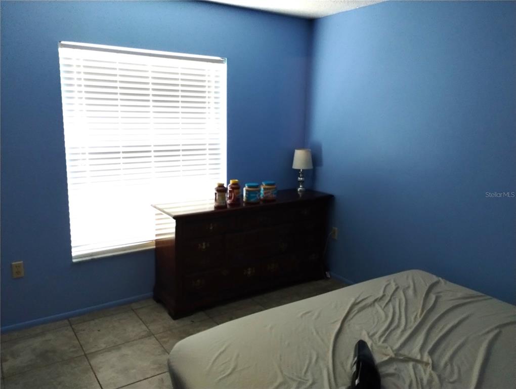 11543 Orleans Lane, Unit B Port Richey, FL 34668 - Photo 7 of 11 a bed sitting in a bedroom next to a window