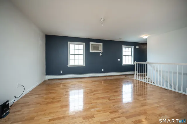 a view of empty room with wooden floor and fan