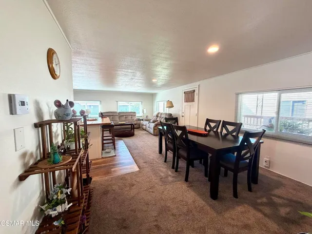 a view of a dining room and livingroom with furniture a rug a painting and a chandelier