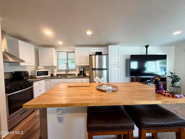 a kitchen with stainless steel appliances a dining table and chairs