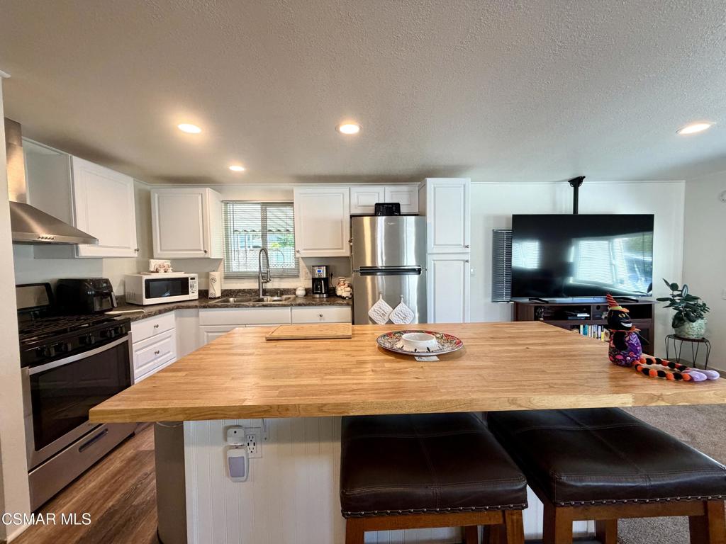 6480 Katherine Road, Unit 6 Simi Valley, CA 93063 - Photo 10 of 34 a kitchen with stainless steel appliances a dining table and chairs