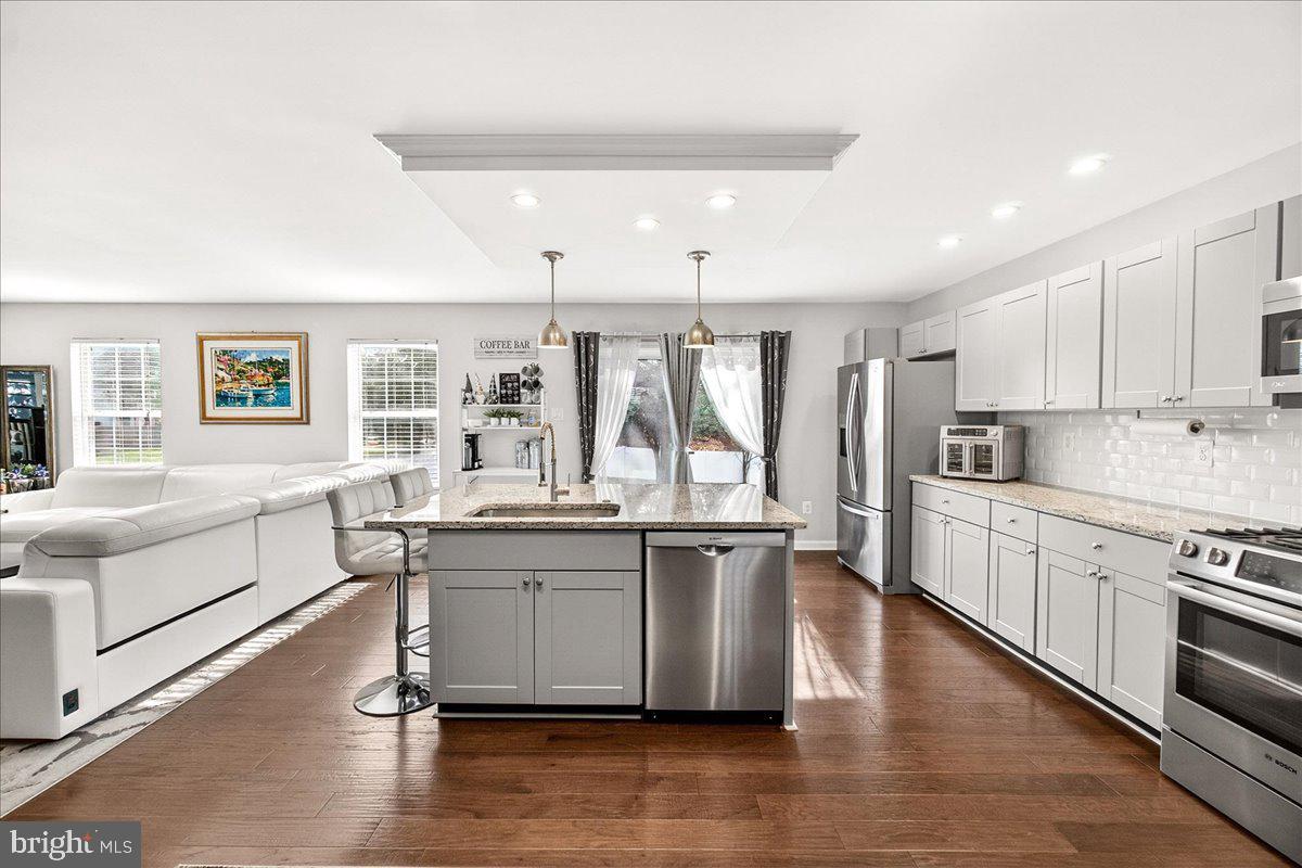 6303 Edgeware Court Frederick, MD 21703 - Photo 21 of 74 a large white kitchen with stainless steel appliances granite countertop a stove top oven a sink dishwasher and cabinets with wooden floor