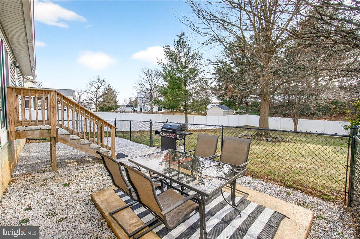 6303 Edgeware Court Frederick, MD 21703 - Photo 46 of 74 a view of a patio with dining table and chairs with wooden floor and fence