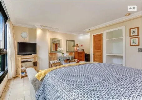 a bedroom with a bed and flat tv screen on the dresser