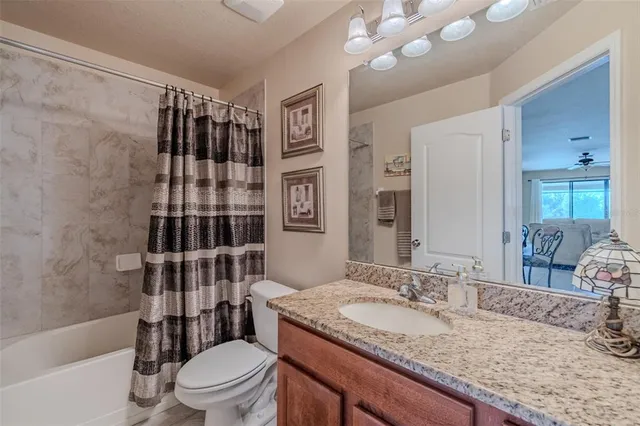a bathroom with a granite countertop sink toilet mirror and shower