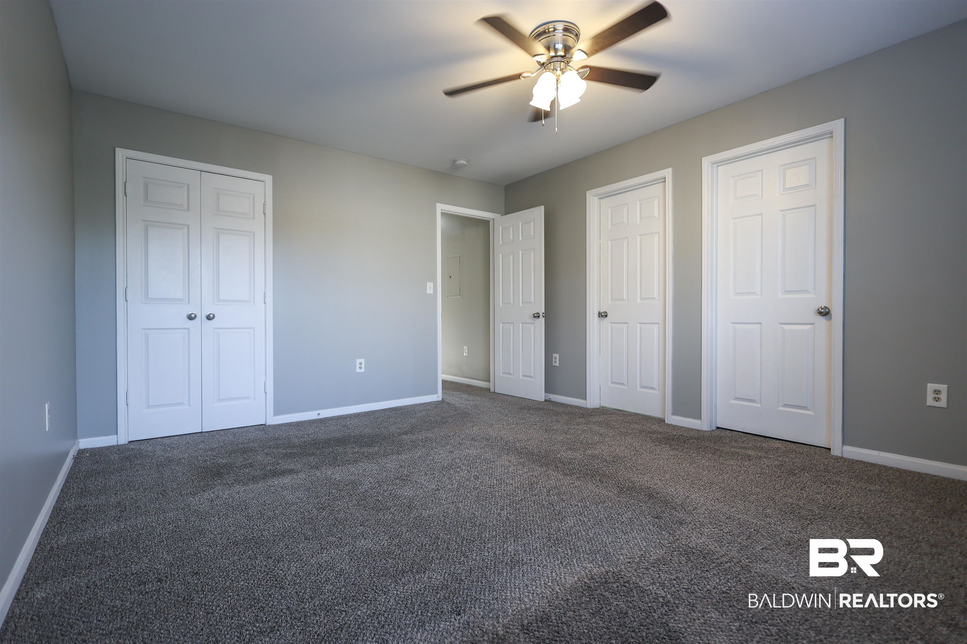 1517 Regency Road, Unit 125 Gulf Shores, AL 36542 - Photo 12 of 26 Unfurnished bedroom featuring two closets, dark colored carpet, and ceiling fan