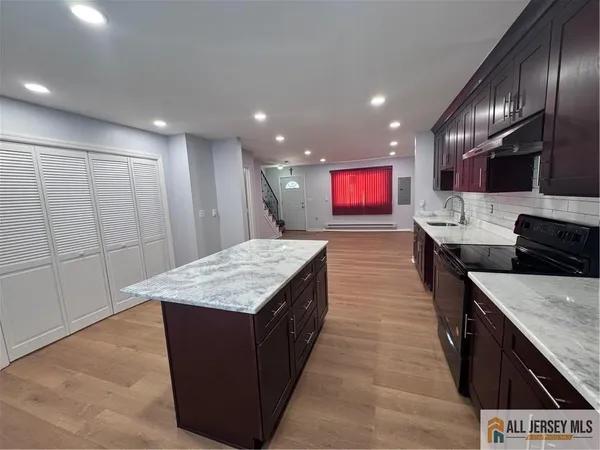 a large kitchen with kitchen island a sink wooden floor and a refrigerator