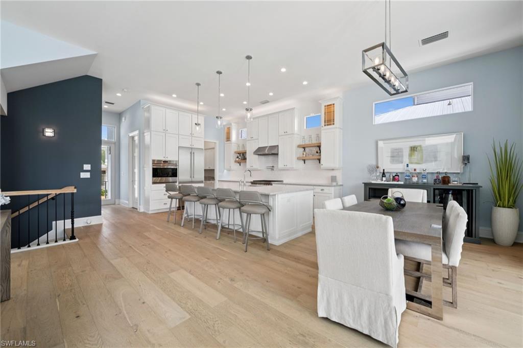 26659 Hickory Boulevard Bonita Springs, FL 34134 - Photo 7 of 46 a kitchen with kitchen island stainless steel appliances a dining table chairs and white cabinets