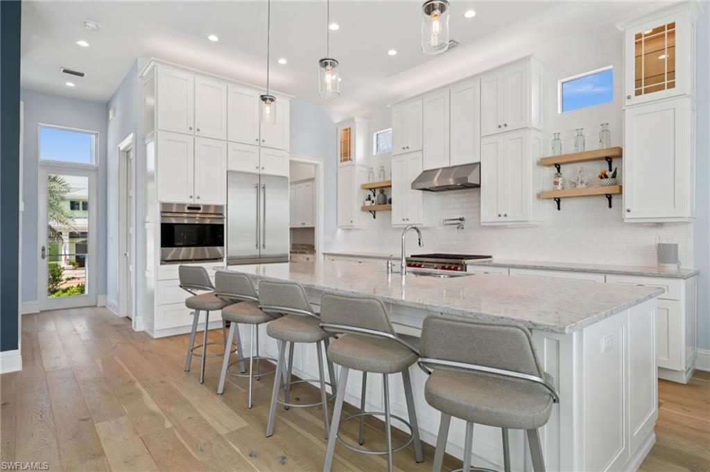26659 Hickory Boulevard Bonita Springs, FL 34134 - Photo 8 of 46 a kitchen with stainless steel appliances granite countertop a stove refrigerator a sink dishwasher and a dining table with wooden floor