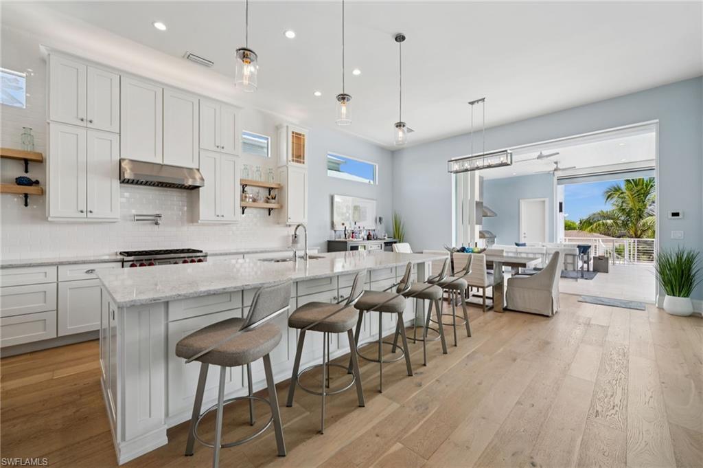 26659 Hickory Boulevard Bonita Springs, FL 34134 - Photo 10 of 46 a kitchen with stainless steel appliances kitchen island granite countertop a table chairs sink and cabinets