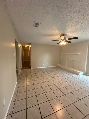 a view of an empty room and chandelier fan